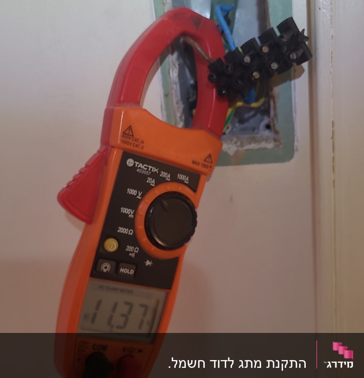 מד מתח מחובר לחוטי חשמל בקיר